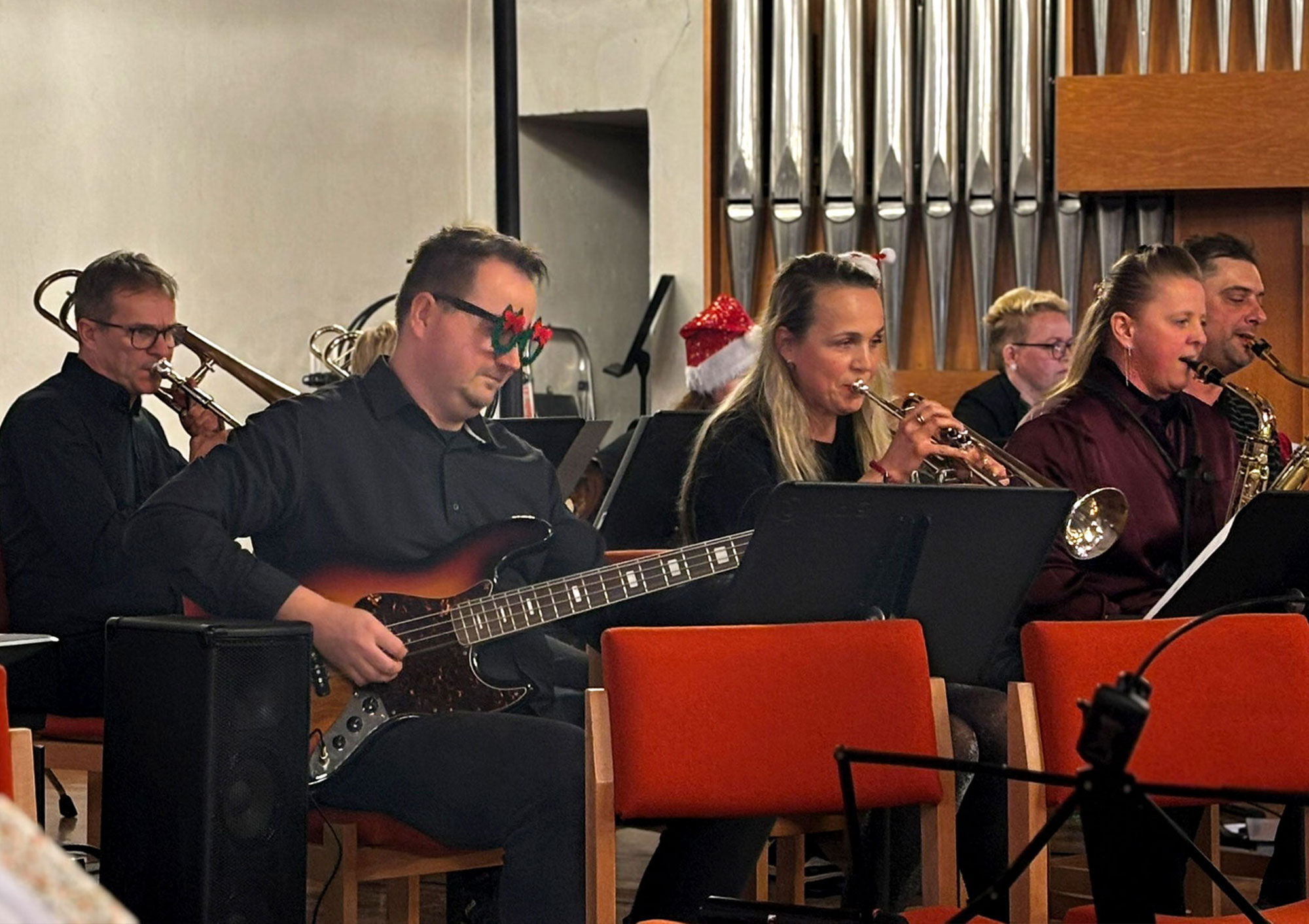 Musikerinnen und Musiker spielen auf Bassgitarre, Trompeten und Saxophonen